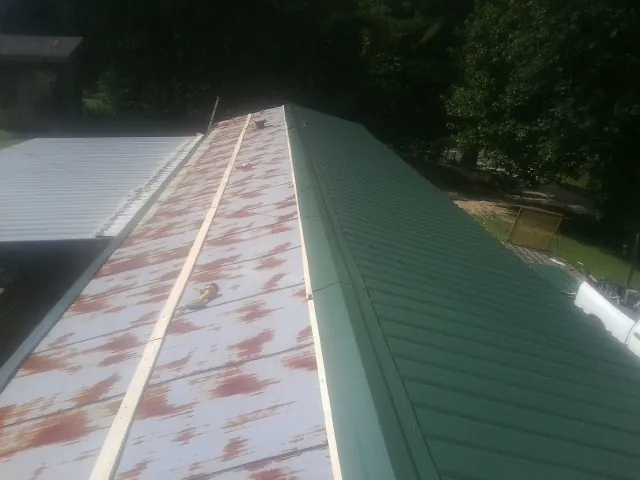 Old rusted panels beside newly installed green metal roofing — Wind Damage Roof Repair by Roofing Brothers in Fountain Green