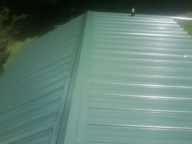 New green metal panels meeting at the ridge of a roof — Flat Roof Repair work by our crew in Fountain Green
