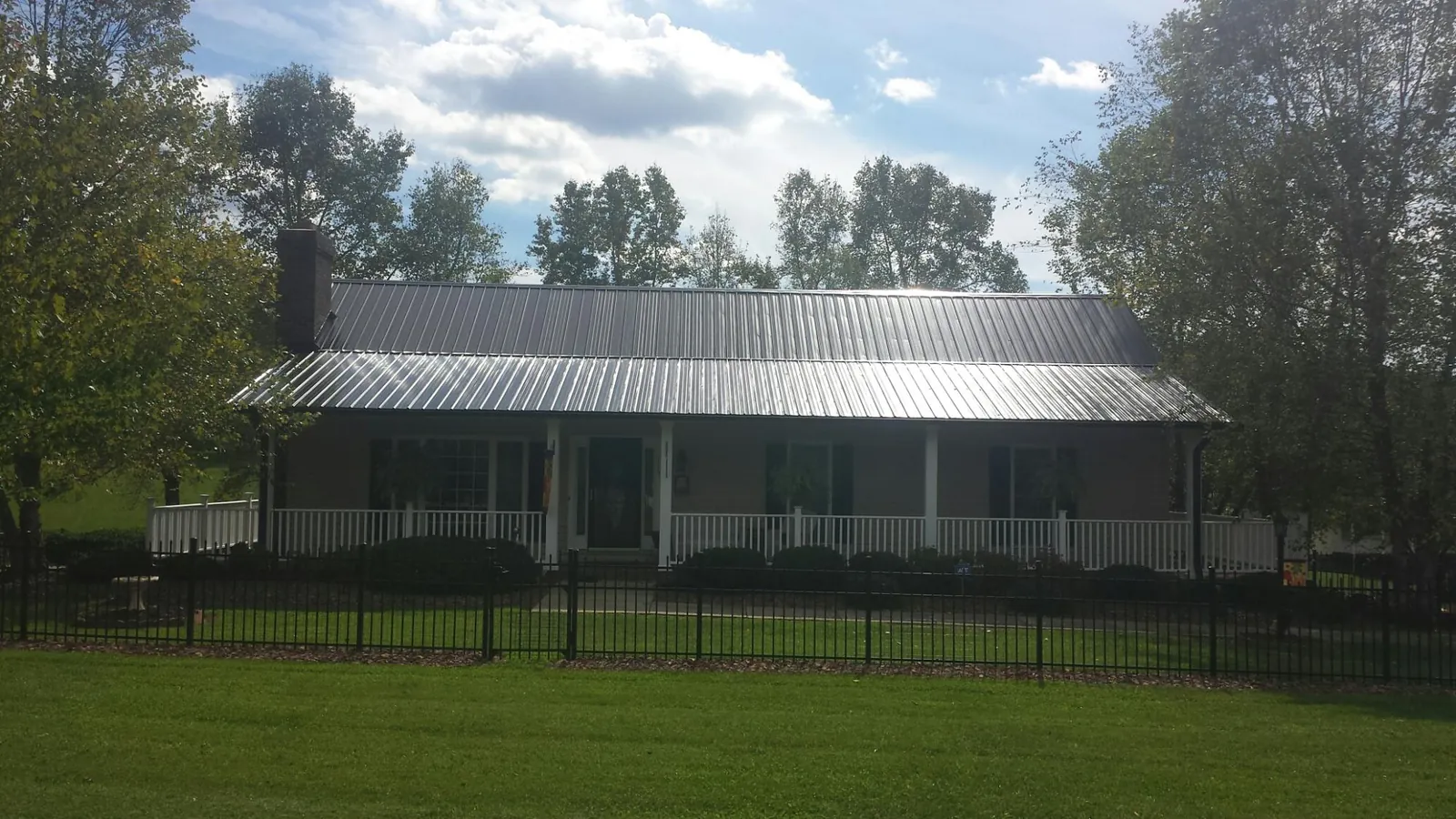 Gray metal roof on a brick ranch with a full width front porch — Gutter Guard Installation work by our crew in Fountain Green