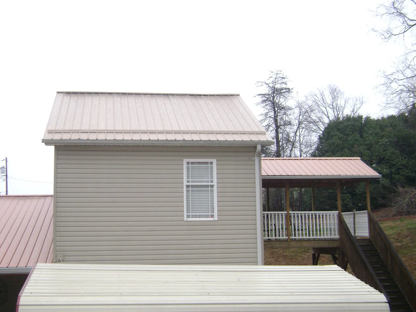 Tan metal roofs on a two story addition and attached porch, from a Roof Replacement job in Fountain Green