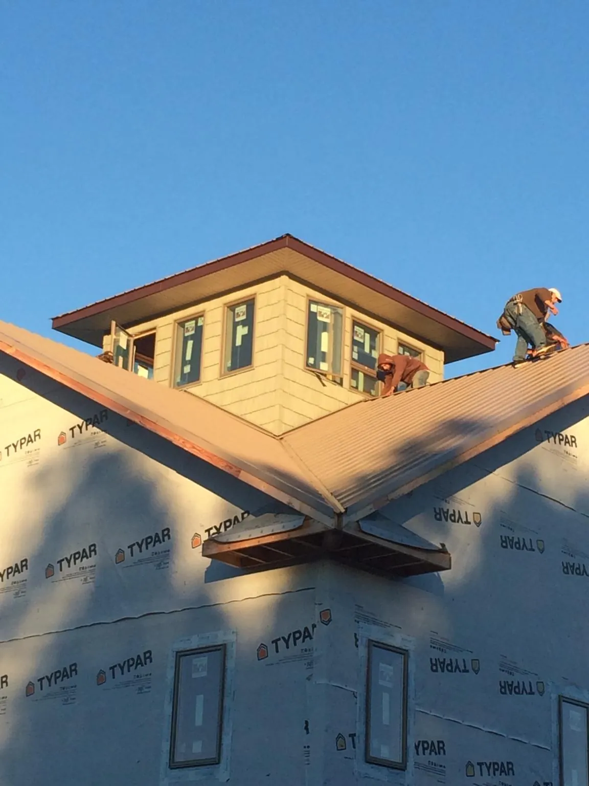 Roofers working around a rooftop cupola on a new metal roof at sunset — Roof Waterproofing in Fountain Green by Roofing Brothers